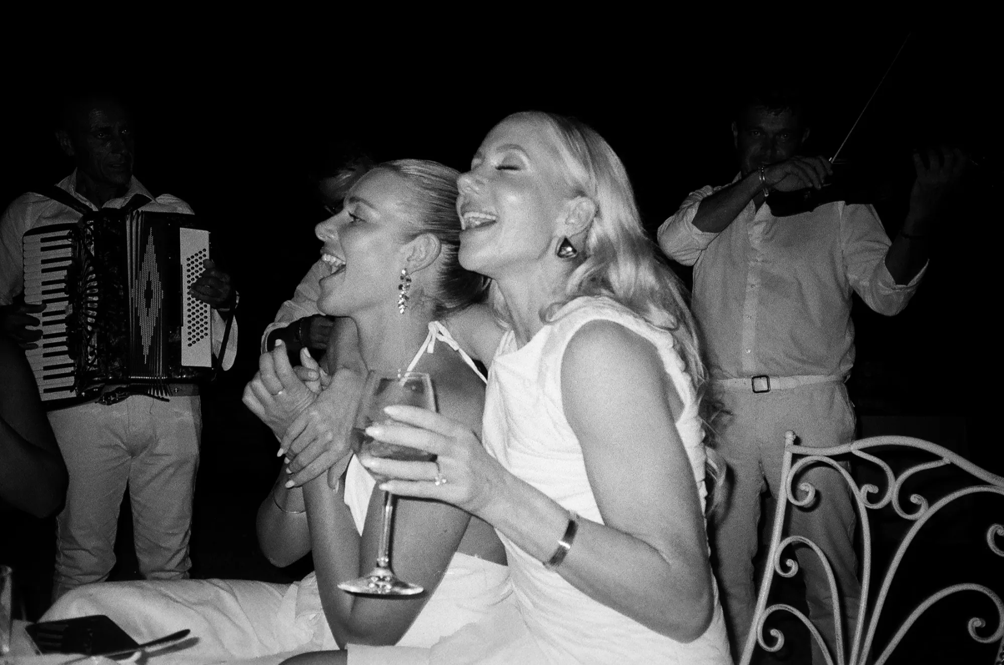 A couple and their guests laughing during a candlelit wedding reception with live music